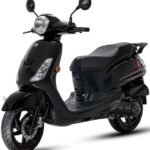 Zwarte moderne scooter met ronde koplamp en spiegels, schuin van voren op witte achtergrond.