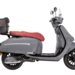 Grijze retro-scooter met rood zadel, topkoffer en windscherm, zijaanzicht.