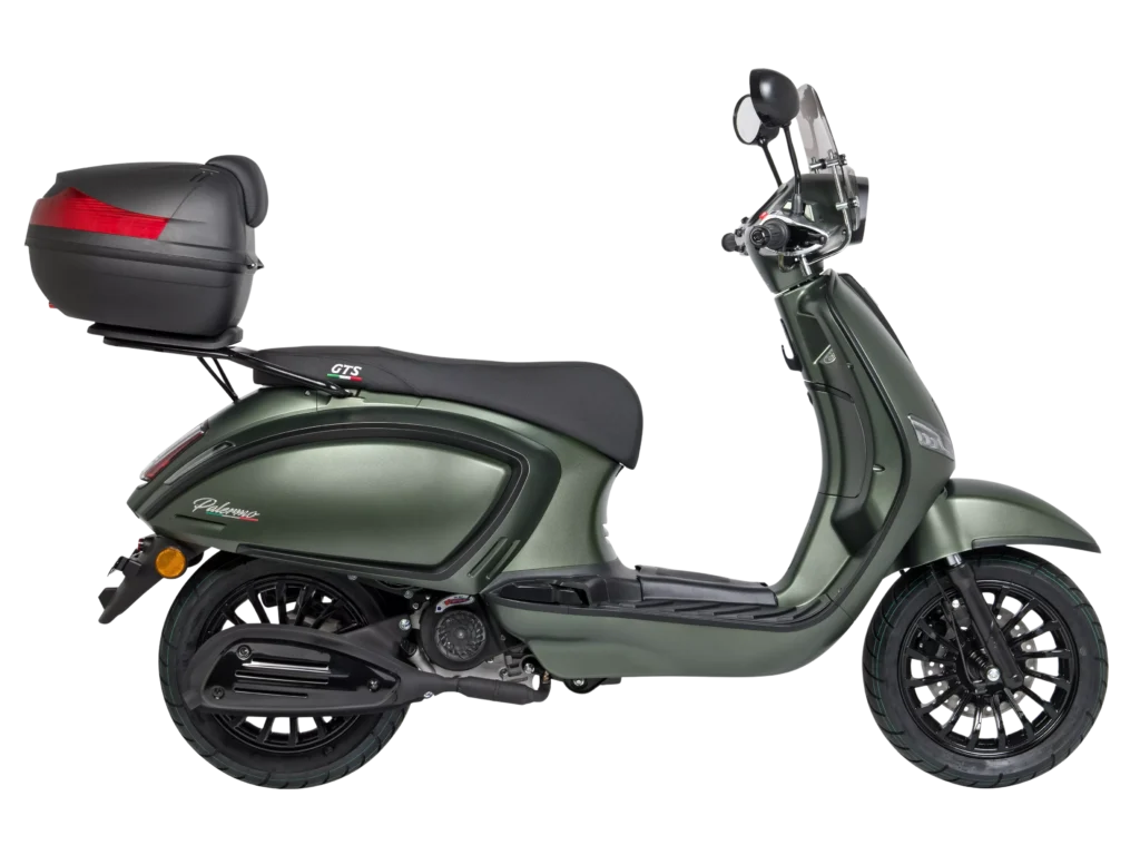 Groene retro-scooter in zijaanzicht met topkoffer, windscherm en zwarte velgen op witte achtergrond.