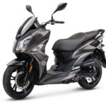 Donkergrijze, moderne scooter met sportief ontwerp en dubbele koplampen op een witte achtergrond.