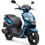 Blauwe moderne scooter met zwart zadel en spiegels, studiofoto op witte achtergrond.