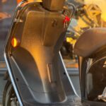 Close-up van de voetenruimte van een scooter met sleutels in het contact, in warm avondlicht