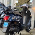 Donkerblauwe stadsscooter met spiegels en kenteken, op de middenstandaard voor een showroom.