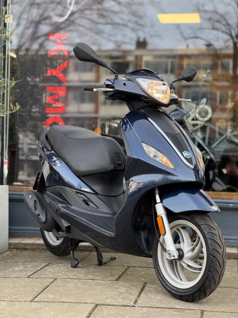 Donkerblauwe scooter op standaard, geparkeerd voor een etalage met reflecties.