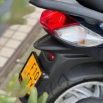 Close-up van de achterkant van een scooter met rood achterlicht, kentekenplaat en achterwiel
