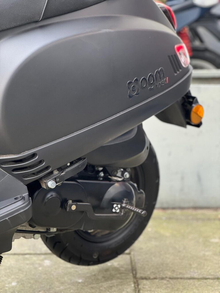 Close-up van achterzijde van een matzwarte scooter met motorblok en achterwiel.