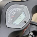 Close-up van het instrumentenpaneel van een motor of scooter met analoge toerenteller en LCD-display.