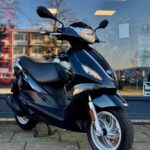 Zwarte scooter op standaard voor een winkelruit, close-up van de voorkant en voorwiel.