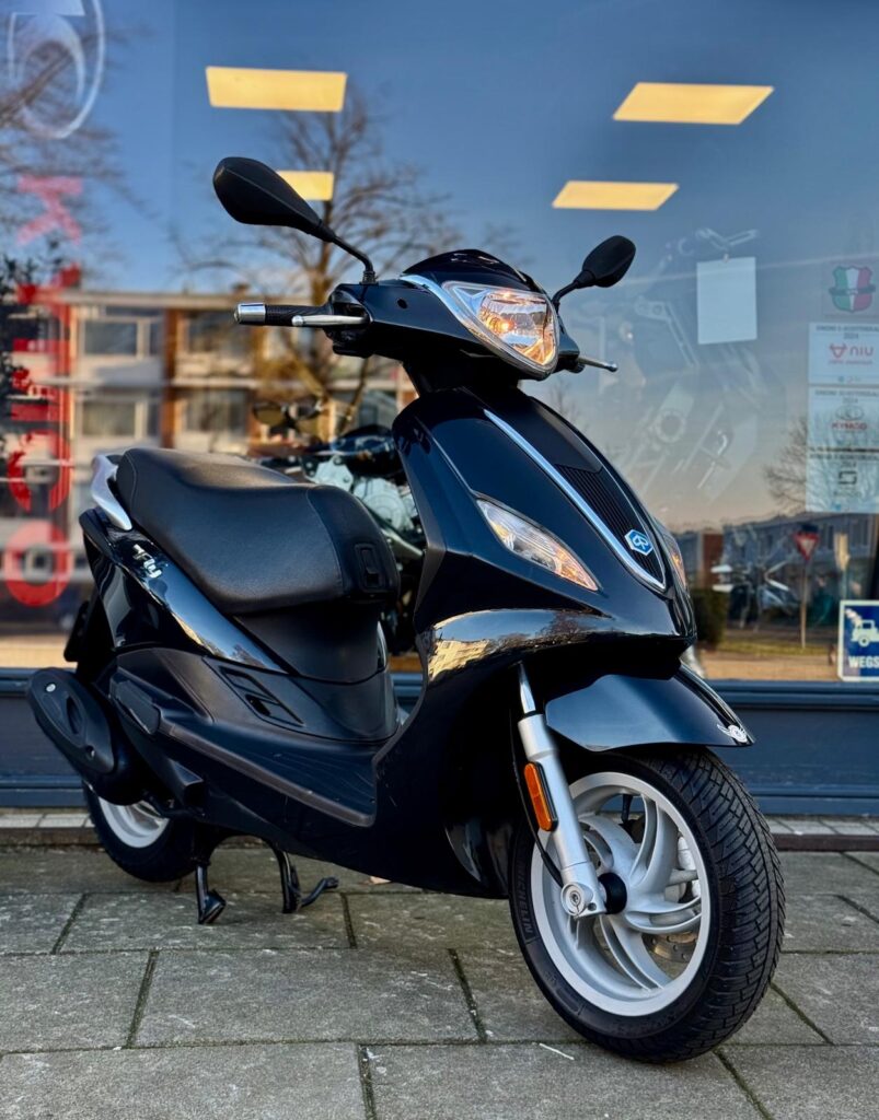 Zwarte scooter op standaard voor een winkelruit, close-up van de voorkant en voorwiel.