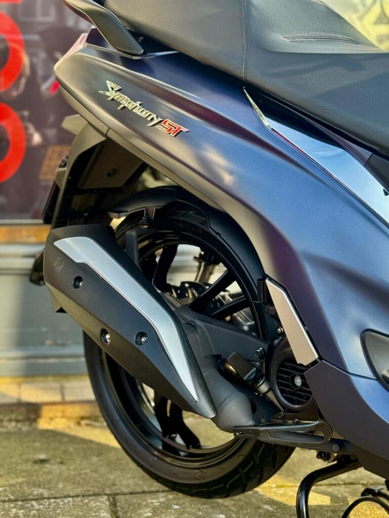 Close-up van het achterwiel, uitlaat en zadel van een blauwe scooter, Symphony ST.