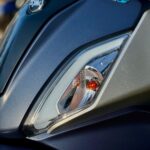 Close-up van de voorzijde van een SYM-scooter met koplamp en Euro 5-sticker.