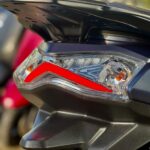 Close-up van de achterlichtunit van een scooter met helder LED-glas en rood accentelement.