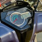 Close-up van het scooterdashboard met analoge snelheidsmeter, digitaal display en contactsleutel.