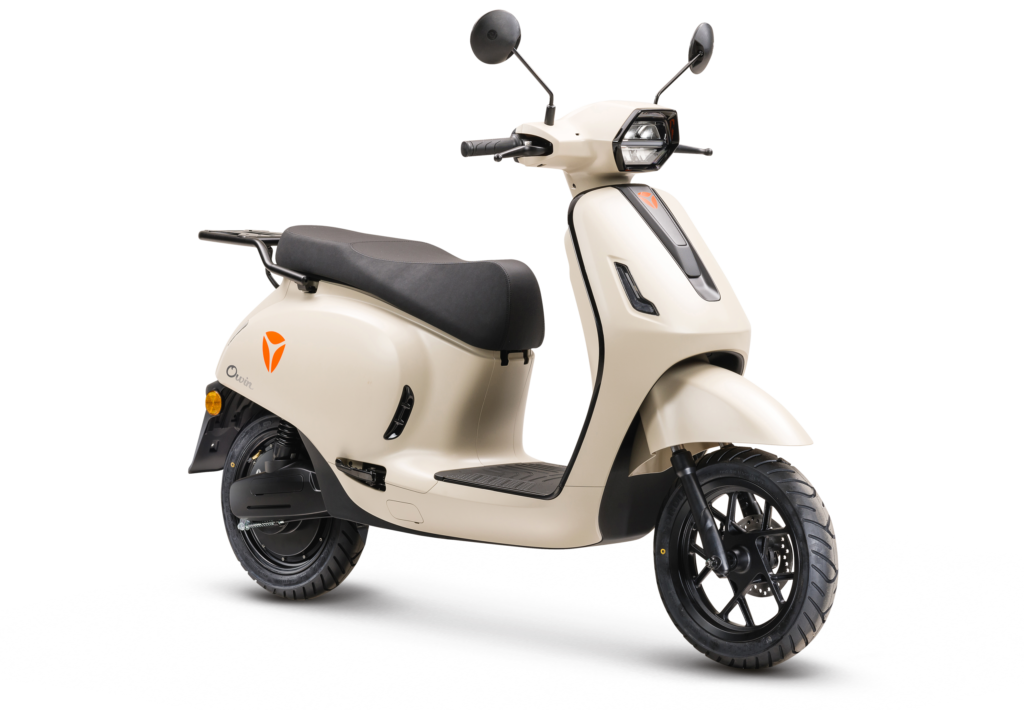 Crèmekleurige elektrische scooter met ronde spiegels en zwart zadel, schuin van voren gezien.