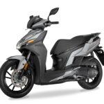 Moderne grijze scooter met sportief design, driekwart vooraanzicht op witte achtergrond.