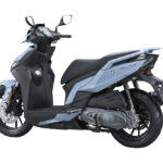 Lichtblauwe moderne scooter met zwarte accenten, gezien schuin van achteren op witte achtergrond.