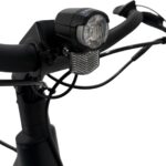 Close-up van een fietsstuur met voorlamp, reflector en kabels, in zwarte uitvoering.
