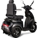 Zwarte driewielige scootmobiel met hoge rugleuning, armleuningen en spiegels, rechtsachteraanzicht.