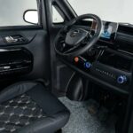 Interieur van compacte auto met stuur, infotainmentscherm, airco-knoppen en zwarte stoelbekleding.