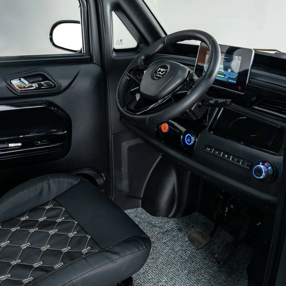 Interieur van compacte auto met stuur, infotainmentscherm, airco-knoppen en zwarte stoelbekleding.