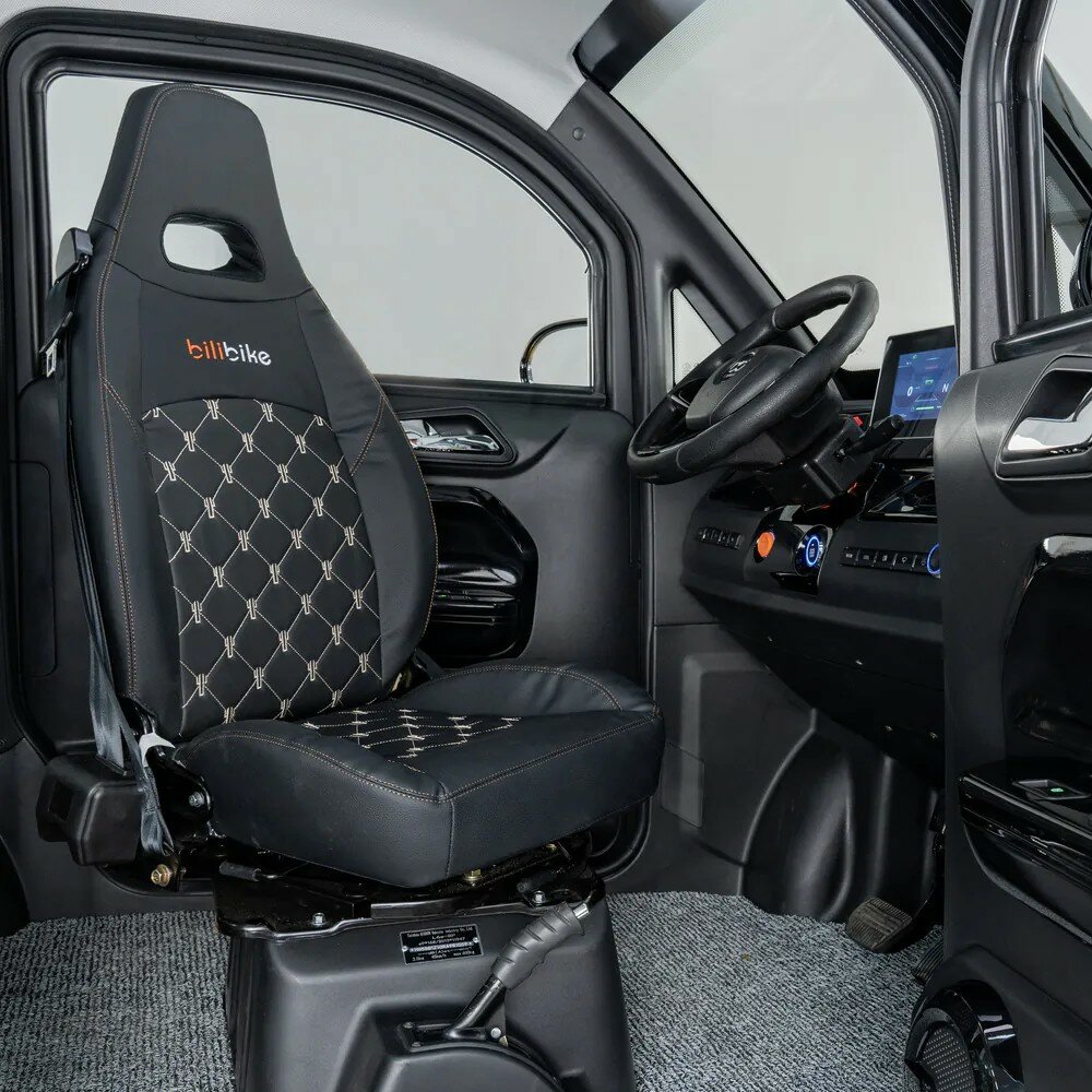 Interieur van een compacte elektrische microauto met luxe bestuurdersstoel, stuur en infotainmentscherm.