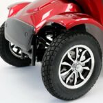 Close-up van het voorwiel met profielband en chroomvelg onder een rood spatbord.