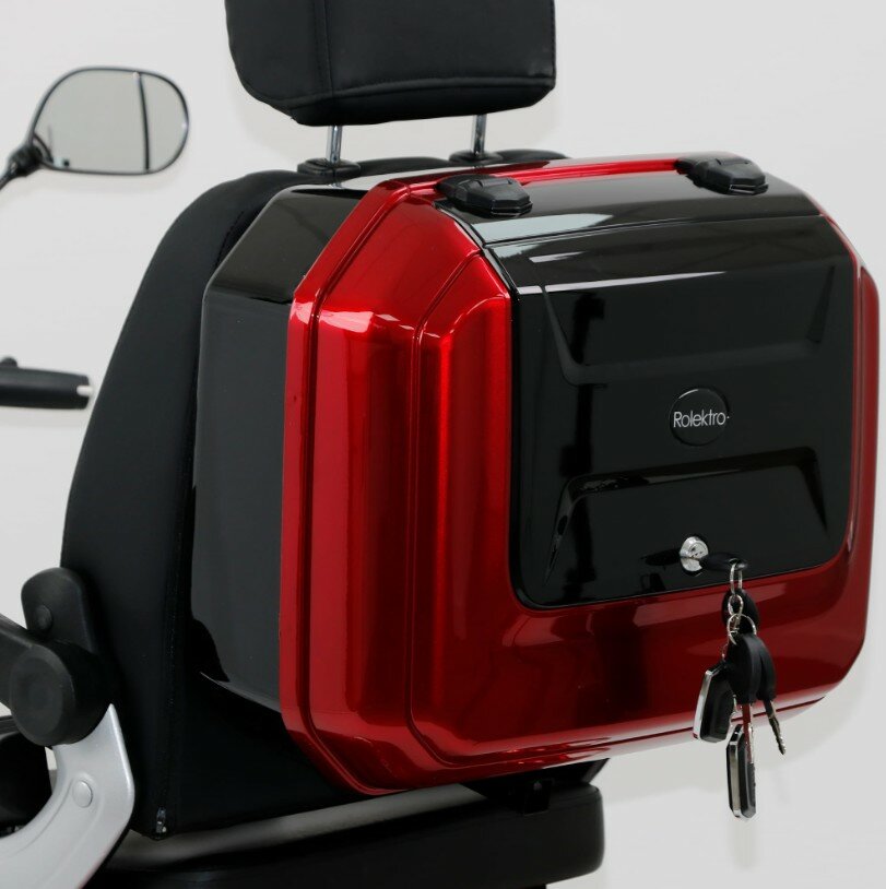 Rood-zwarte topkoffer met sleutels in het slot, gemonteerd achterop een scooterstoel.