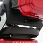 Close-up van de achterzijde van een scootmobiel: zitting, beugel en open rode koffer met achterlicht.
