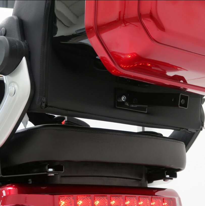 Close-up van de achterzijde van een scootmobiel: zitting, beugel en open rode koffer met achterlicht.