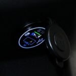 Close-up van een verlichte USB-A en USB-C (PD) oplaadpoort met open rubberen afdekdop.