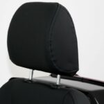 Close-up van een zwarte verstelbare hoofdsteun op een stoel met metalen steunen.