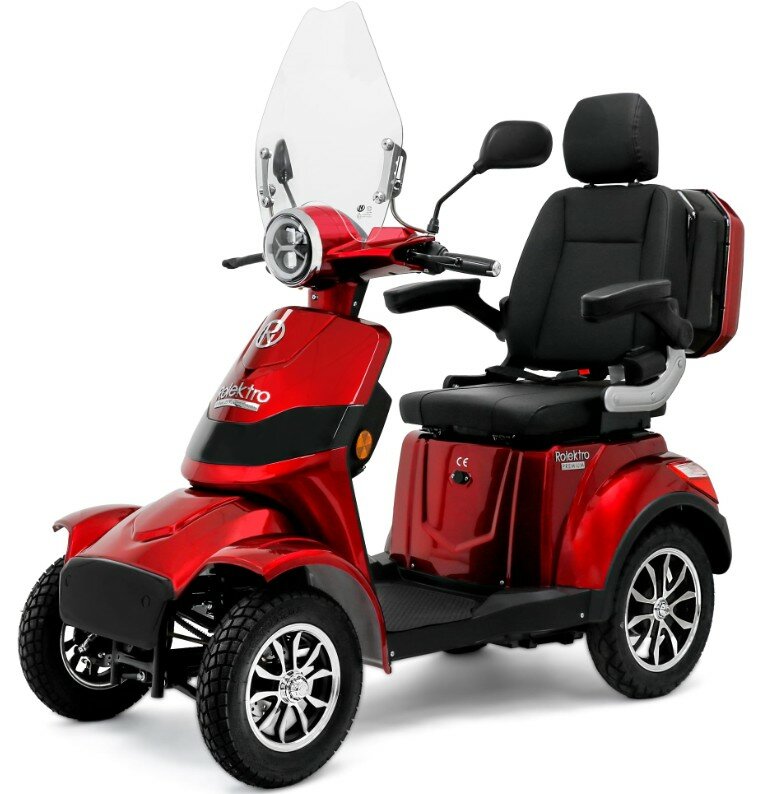 Rode vierwielige scootmobiel met windscherm, comfortabele stoel met armleuningen en koffer.