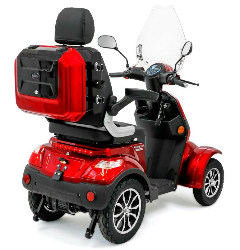 Rode elektrische scootmobiel met windscherm, spiegels en topkoffer, achteraanzicht.
