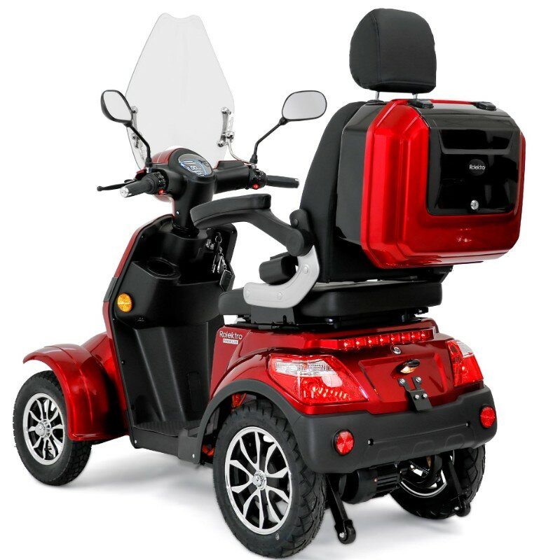 Rode vierwielige scootmobiel met hoge rugleuning, windscherm en achterkoffer, driekwart van achteren.