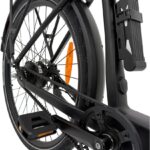 Close-up van een zwarte stadsfiets met riemaandrijving, achterwiel met schijfrem, bagagedrager, pedaal en oranje reflector.