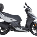 Zwart-witte scooter met topkoffer, zijaanzicht op witte achtergrond.