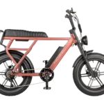 Roze moped-stijl e-bike met dikke banden, lange zadelbank, spatborden, bagagedrager, voorlamp en accu op het frame.