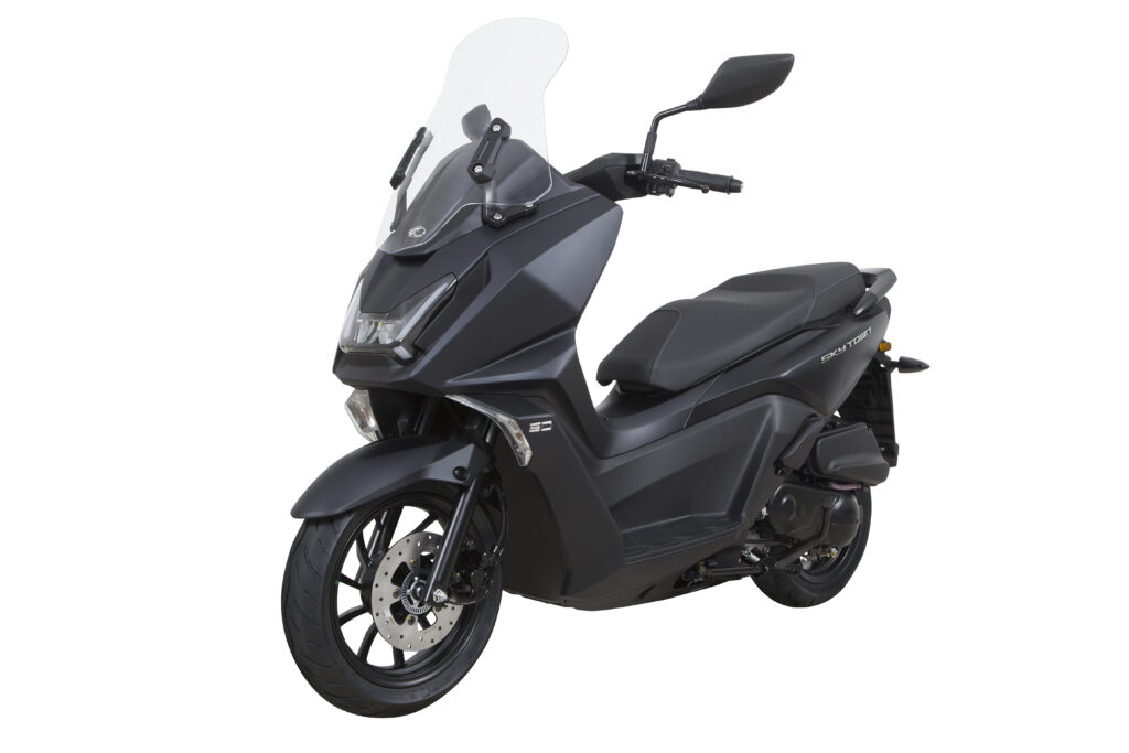 Zwarte maxiscooter met hoge ruit en schijfrem, driekwart vooraanzicht op witte achtergrond.