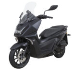 Zwarte maxiscooter met hoge ruit en schijfrem, driekwart vooraanzicht op witte achtergrond.