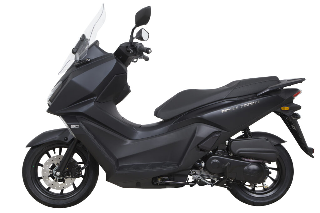 Zijaanzicht van een matzwarte motorscooter met ruit en schijfremmen, gefotografeerd tegen een witte achtergrond.