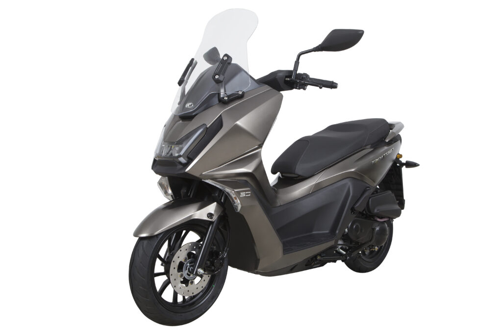 Moderne bronsgrijze maxi-scooter met hoog windscherm en schijfrem, schuin van voren op witte achtergrond.