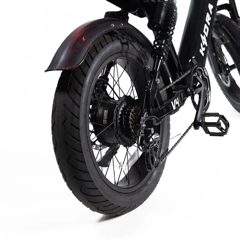 Close-up van het achterwiel van een elektrische vouwfiets met dikke band, ketting, derailleur, spatbord en naafmotor.