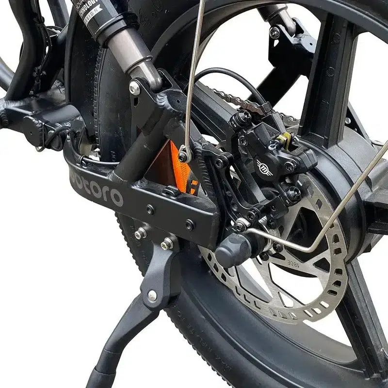 Detail van achterwiel van elektrische fiets met schijfrem, vering en zijstandaard.