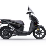 Moderne zwarte e-scooter met windscherm, zijaanzicht op witte achtergrond.