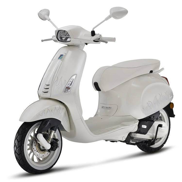 Witte retro scooter met subtiele vlammenprint, schuin van rechts gefotografeerd op witte achtergrond.