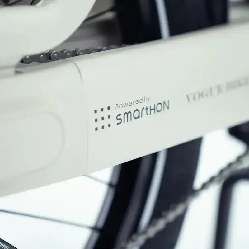Close-up van een witte kettingkast van een e-bike met 'Powered by Smarthon' en de fietsketting zichtbaar.
