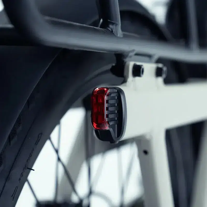 Close-up van een rood achterlicht op een moderne fiets, gemonteerd bij het achterwiel.