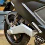 Close-up van het achterwiel, vering en middenbok van een zwarte elektrische scooter.