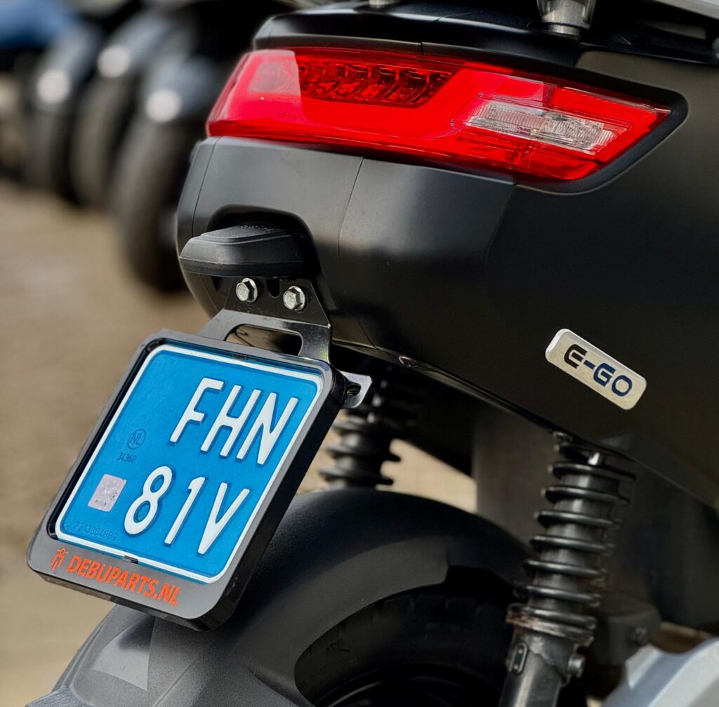 Close-up van de achterzijde van een elektrische scooter met rood achterlicht en blauwe kentekenplaat.