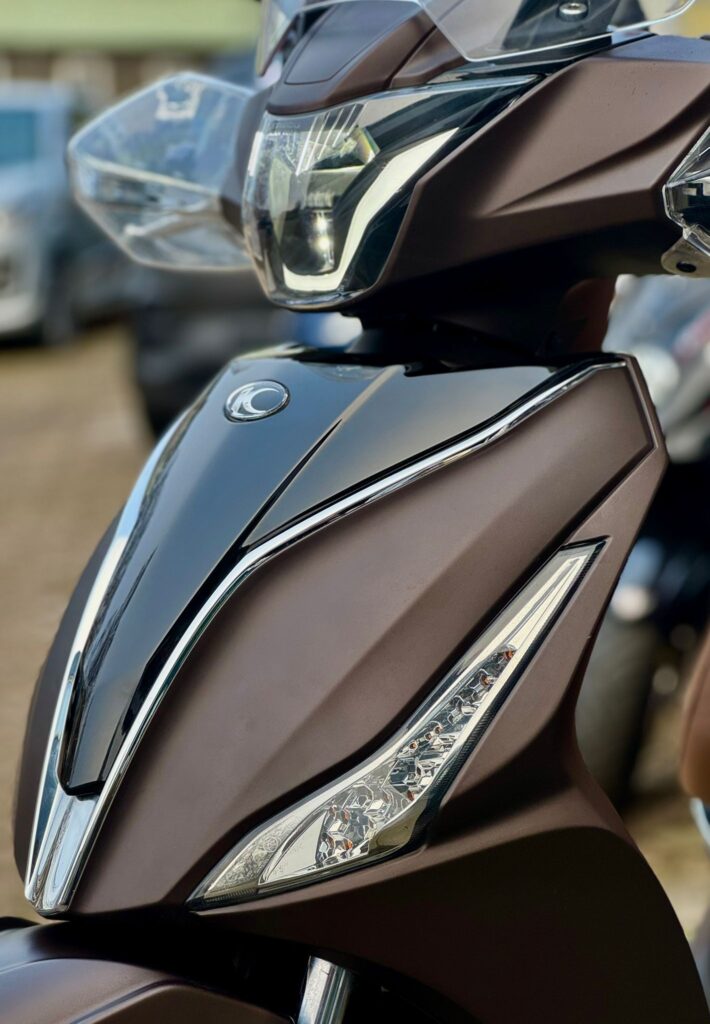 Close-up van de voorkant van een bruine scooter met moderne LED-koplamp en chroomaccenten